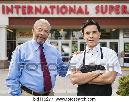 Stock Photo - Businessman and worker smiling outside grocery store. Fotosearch