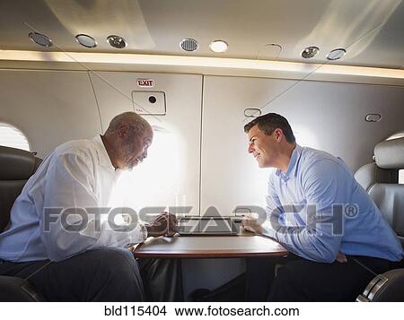 Businessmen talking on airplane View Large Photo Image Picture - Businessmen talking on airplane. Fotosearch