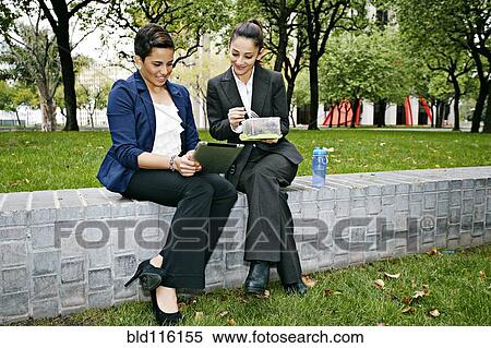 Stock Photography - Businesswomen using tablet computer outdoors. Fotosearch