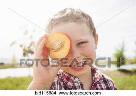 Caucasian boy holding fruit over eyes View Large Photo Image Picture - Caucasian boy holding fruit over eyes. Fotosearch