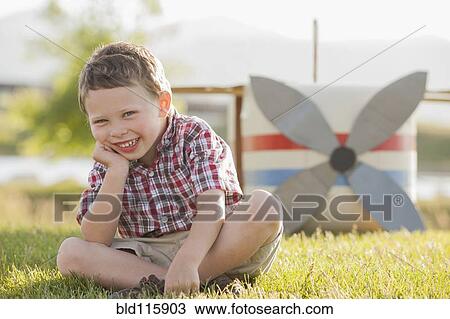 Stock Image - Caucasian boy smiling in grass. Fotosearch