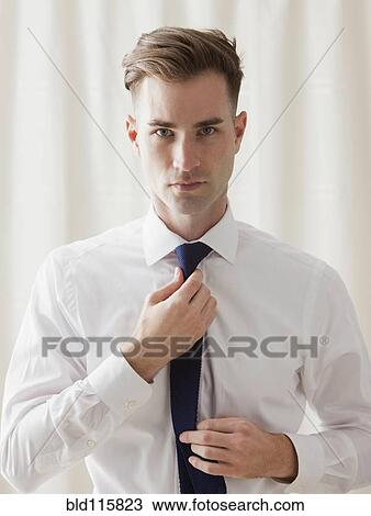 Stock Image - Caucasian businessman adjusting his tie. Fotosearch