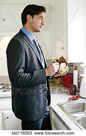 Stock Image - Caucasian businessman eating take out food. Fotosearch