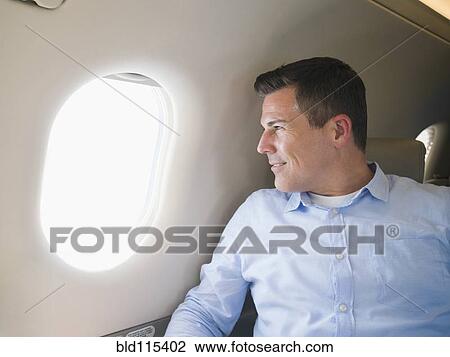 Caucasian businessman looking out airplane window View Large Photo Image Stock Image - Caucasian businessman looking out airplane window. Fotosearch