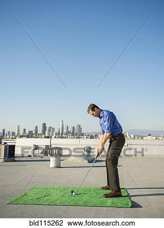 Caucasian businessman playing golf on urban rooftop View Large Photo Image Stock Image - Caucasian businessman playing golf on urban rooftop. Fotosearch