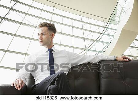 Stock Photograph - Caucasian businessman sitting on sofa in lobby. Fotosearch