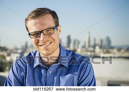 Stock Photo - Caucasian businessman smiling on urban rooftop. Fotosearch