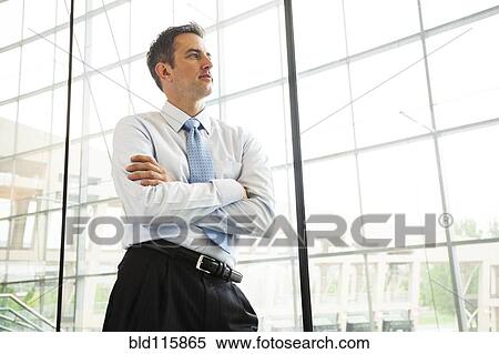 Stock Photography - Caucasian businessman standing at window. Fotosearch