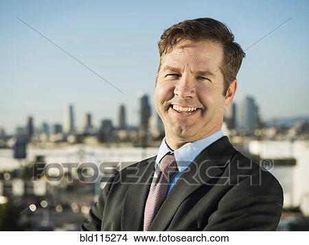 Picture - Caucasian businessman standing on urban rooftop. Fotosearch