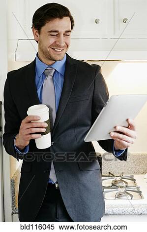 Stock Photography - Caucasian businessman using tablet computer in kitchen. Fotosearch
