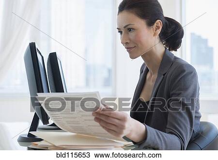 Stock Image - Caucasian businesswoman working at desk. Fotosearch