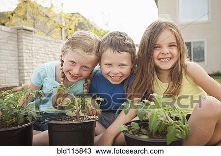 Stock Image - Caucasian children gardening in backyard. Fotosearch