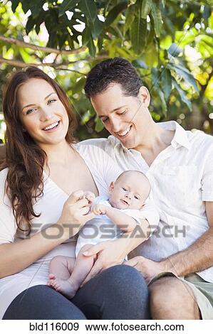 Stock Photo - Caucasian couple holding baby outdoors. Fotosearch