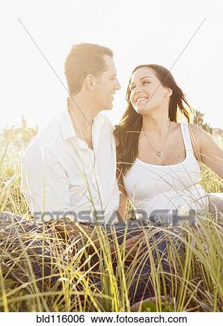 Caucasian couple sitting in tall grass View Large Photo Image Stock Photograph - Caucasian couple sitting in tall grass. Fotosearch
