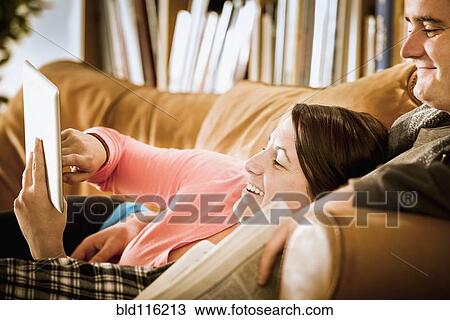 Stock Image - Caucasian couple using digital tablet on sofa. Fotosearch