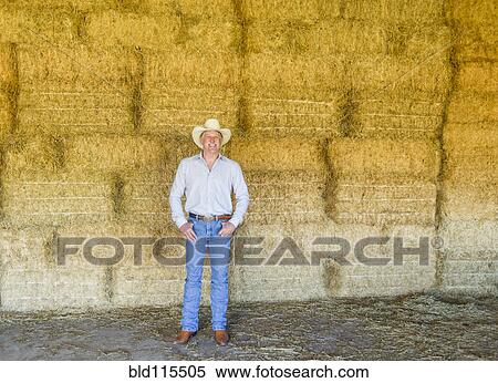 Caucasian farmer standing with hay bales View Large Photo Image Stock Photography - Caucasian farmer standing with hay bales. Fotosearch