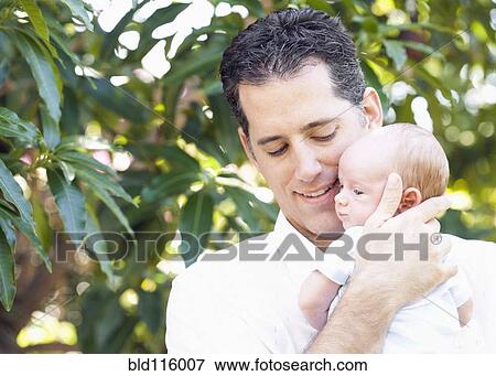 Caucasian father holding baby outdoors View Large Photo Image Stock Photo - Caucasian father holding baby outdoors. Fotosearch