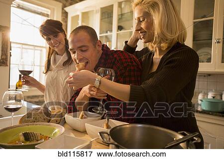 Caucasian friends eating together in kitchen View Large Photo Image Stock Photo - Caucasian friends eating together in kitchen. Fotosearch