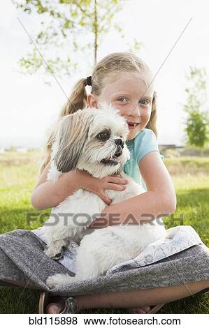 Stock Photo - Caucasian girl hugging dog in grass. Fotosearch