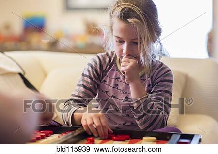 Stock Photo - Caucasian girl playing backgammon on sofa. Fotosearch