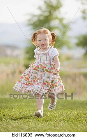 Stock Image - Caucasian girl running in grass. Fotosearch