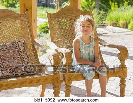 Stock Image - Caucasian girl sitting on patio. Fotosearch