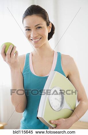 Stock Photography - Caucasian holding apple and scale. Fotosearch