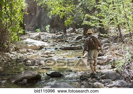 Caucasian man hiking along rocky creek View Large Photo Image Stock Photograph - Caucasian man hiking along rocky creek. Fotosearch