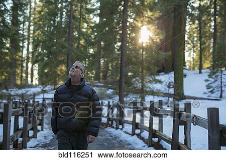 Stock Image - Caucasian man walking in snowy forest. Fotosearch
