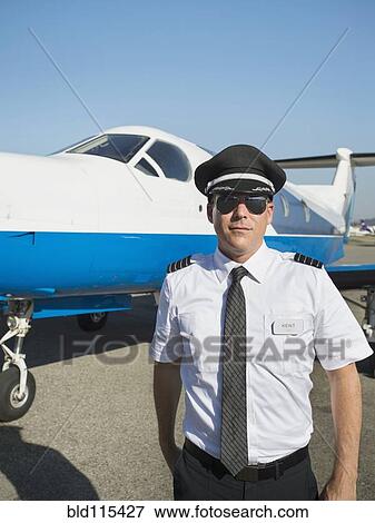 Stock Photo - Caucasian pilot by airplane on runway. Fotosearch
