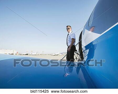 Stock Photography - Caucasian pilot leaving airplane on runway. Fotosearch