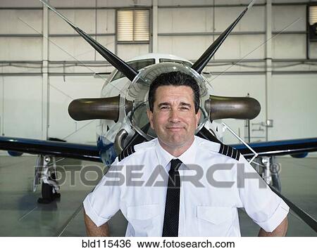 Stock Photograph - Caucasian pilot smiling in hangar. Fotosearch