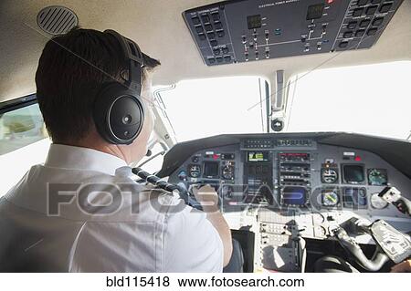 Stock Photo - Caucasian pilot working in airplane cockpit. Fotosearch