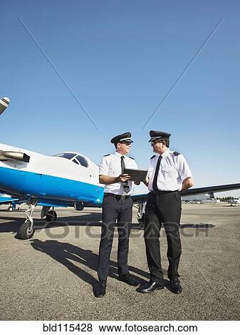 Caucasian pilots using digital tablet on runway View Large Photo Image Stock Photo - Caucasian pilots using digital tablet on runway. Fotosearch