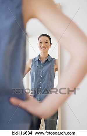 Picture - Caucasian woman admiring herself in mirror. Fotosearch