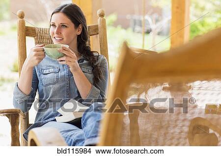 Picture - Caucasian woman having cup of coffee in rocking chair. Fotosearch