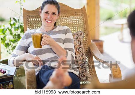 Stock Image - Caucasian woman having cup of coffee on patio. Fotosearch