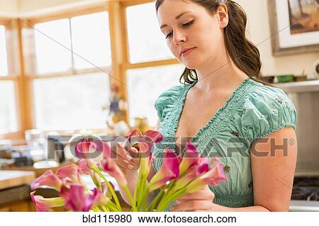 Stock Image - Caucasian woman holding vase of flowers. Fotosearch