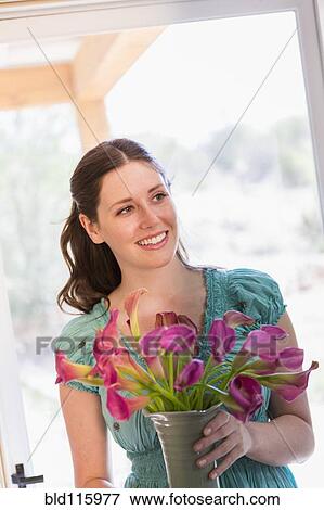 Stock Photo - Caucasian woman holding vase of flowers. Fotosearch