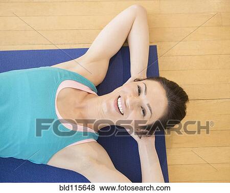 Stock Photo - Caucasian woman laying on yoga mat. Fotosearch