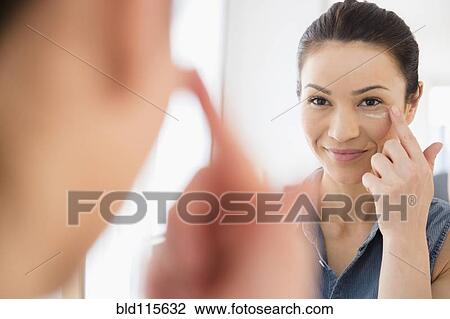 Stock Image - Caucasian woman moisturizing her face. Fotosearch