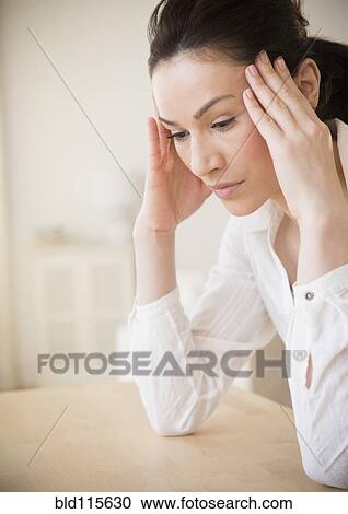 Stock Image - Caucasian woman rubbing her temples. Fotosearch