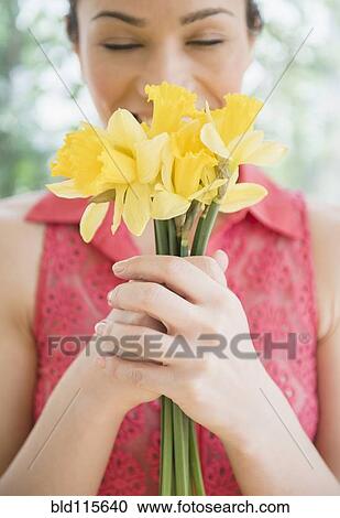 Stock Image - Caucasian woman smelling flowers. Fotosearch