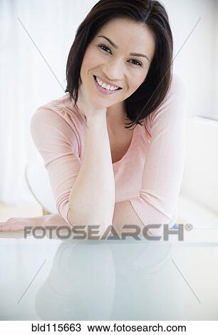 Stock Image - Caucasian woman smiling at desk. Fotosearch