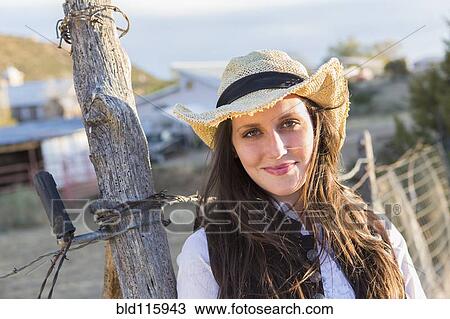 Stock Image - Caucasian woman smiling by barbed wire fence. Fotosearch