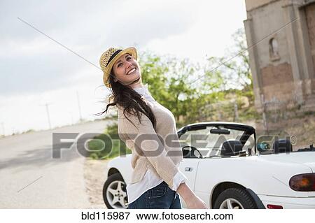Stock Photo - Caucasian woman smiling by convertible. Fotosearch
