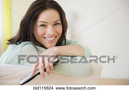 Picture - Caucasian woman watching television on sofa. Fotosearch