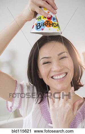 Stock Image - Caucasian woman wearing birthday party hat. Fotosearch