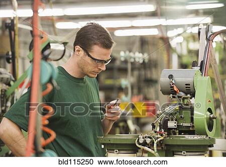 Stock Image - Caucasian worker operating machinery in textile factory. Fotosearch