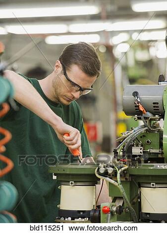 Stock Image - Caucasian worker operating machinery in textile factory. Fotosearch